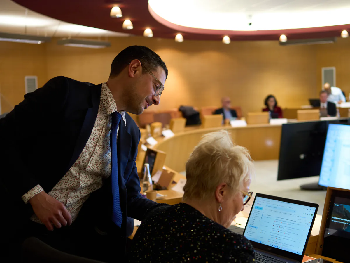 Échange autour d'un ordinateur portable lors d'un événement institutionnel